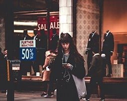 Woman standing on shopping strip using her mobile phone