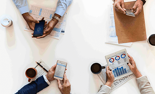 Four people in a meeting using mobile devices