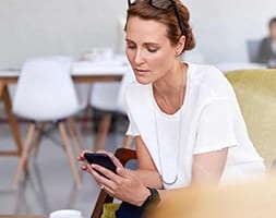 Woman in White Shirt Looking at Her Smart Phone