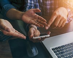 Two People in Discussion with A Smart Phone on Hand and A Laptop