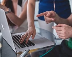Office Meeting with A Laptop on Desk and People Discussing