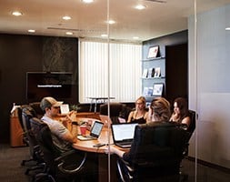 Group of people in an office meeting sitting around a boardroom table with laptops