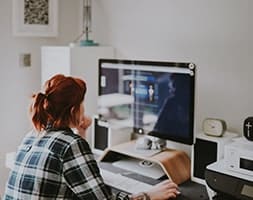 Woman in Checkered Sleeve Looking At Her Computer