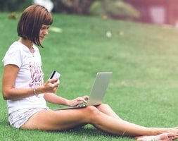 Woman Sitting On Green Grass With A Laptop on The Lap