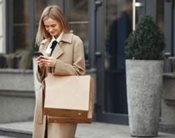 Lady in Coat Smiling While Looking At The Phone