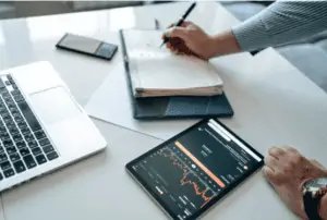 Man Writing Down The Data from the Tablet