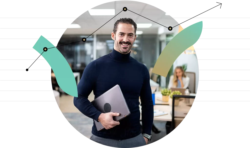 A Man In The Office Setting Holding A Laptop Smiling