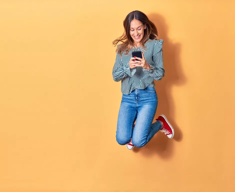 Jump Shot Of A Woman in Stripes Holding A Phone