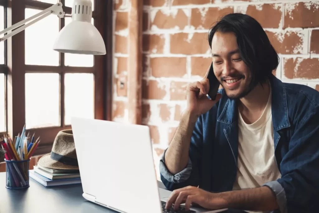 Man Talking on The Phone While Looking at the Laptop