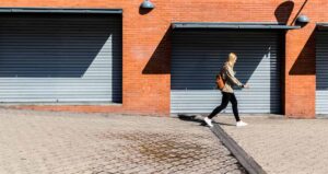 A person passing in front of grey roller shutters