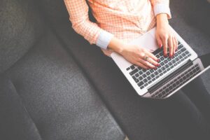 Woman Sitting on A Couch Typing on Her Laptop