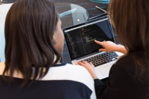 Two Women Discussing About Web Development Codes